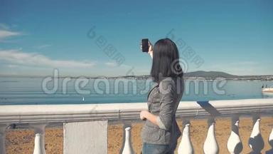 在海滩的地平线上，一位女士用智能手机相机拍照。 年轻女孩拍照